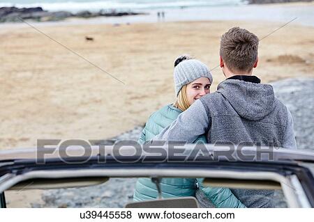 Young couple with arms around each other at beach, Constantine Bay, Cornwall, UK View Large Photo Image Stock Photo - Young couple with arms around each other at beach, Constantine Bay, Cornwall, UK. Fotosearch