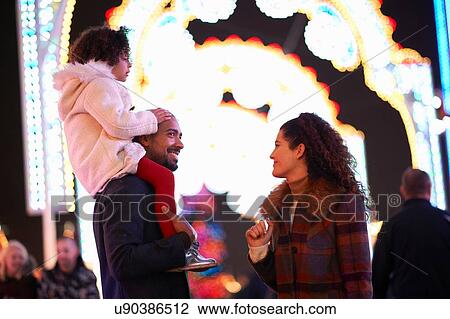 Young family at funfair, father carrying daughter on shoulders View Large Photo Image Stock Image - Young family at funfair, father carrying daughter on shoulders. Fotosearch