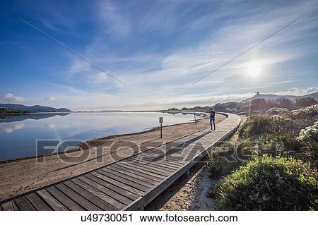 Young female runner running along beach boardwalk, Villasimius, Sardinia, Italy View Large Photo Image Stock Image - Young female runner running along beach boardwalk, Villasimius, Sardinia, Italy. Fotosearch