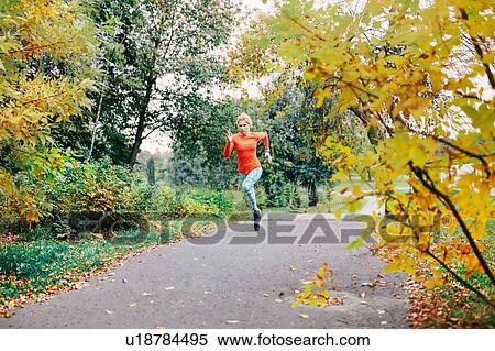 Young female runner running along park path View Large Photo Image Stock Photography - Young female runner running along park path. Fotosearch