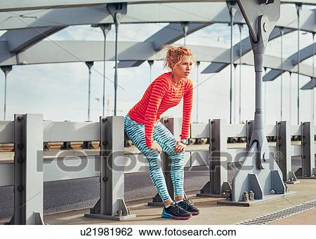 Young female runner taking a break on city footbridge fence View Large Photo Image Stock Image - Young female runner taking a break on city footbridge fence. Fotosearch