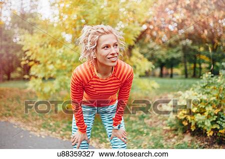 Stock Photo - Young female runner taking a break on park path. Fotosearch