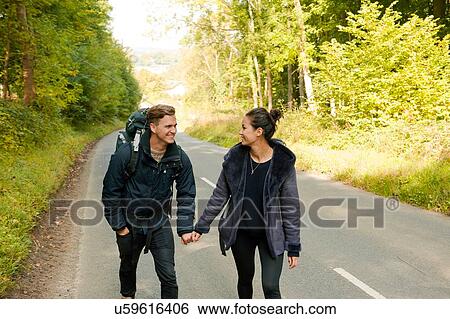 Young hiking couple holding hands on rural road View Large Photo Image Stock Photograph - Young hiking couple holding hands on rural road. Fotosearch