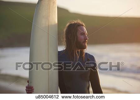 Stock Image - Young male surfer at beach, Devon, England, UK. Fotosearch