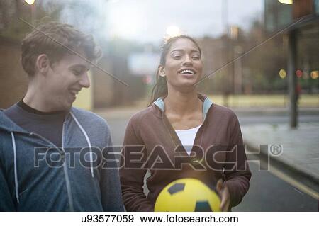 Young man and woman walking in street, holding football View Large Photo Image Stock Photo - Young man and woman walking in street, holding football. Fotosearch
