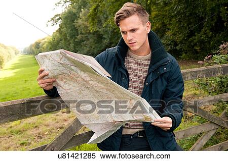 Young man leaning against rural gate reading map View Large Photo Image Stock Photography - Young man leaning against rural gate reading map. Fotosearch