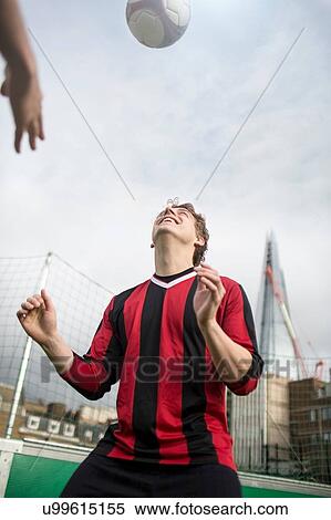 Stock Photography - Young man practising football skills on urban football pitch. Fotosearch