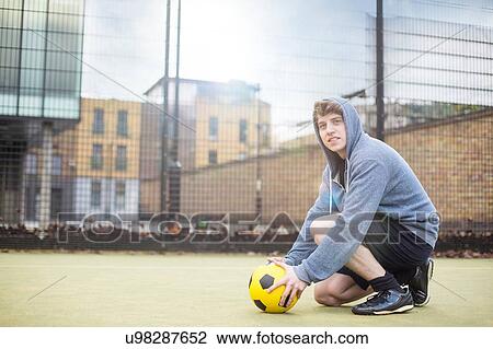 Young man setting football on floor, on urban football pitch View Large Photo Image Stock Image - Young man setting football on floor, on urban football pitch. Fotosearch