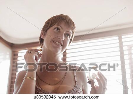 Stock Photography - Young woman applying perfume on neck. Fotosearch
