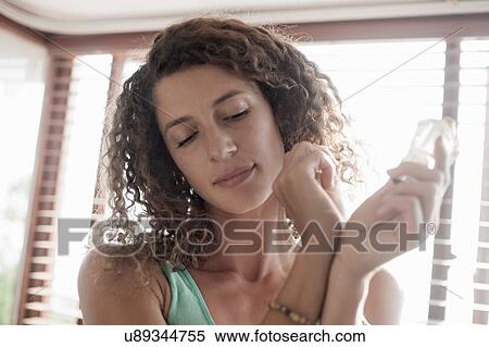 Stock Photography - Young woman applying perfume on wrist. Fotosearch