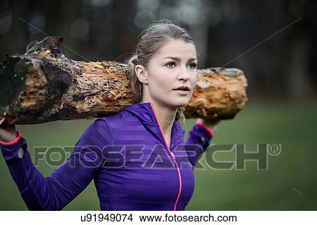 Young woman carrying tree branch on shoulder looking away View Large Photo Image Picture - Young woman carrying tree branch on shoulder looking away. Fotosearch
