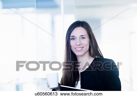 Young woman holding coffee cup and ring binder file looking at camera smiling View Large Photo Image Stock Image - Young woman holding coffee cup and ring binder file looking at camera smiling. Fotosearch