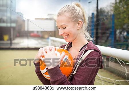 Stock Photography - Young woman holding football, smiling. Fotosearch