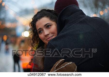 Young woman hugging mid adult man looking away smiling View Large Photo Image Stock Photo - Young woman hugging mid adult man looking away smiling. Fotosearch