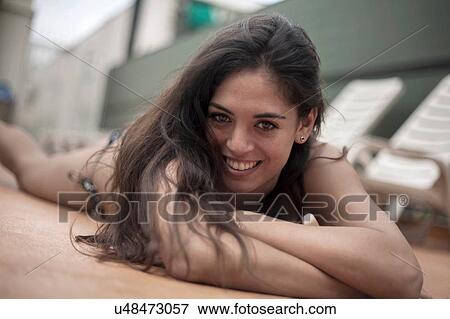 Stock Photo - Young woman in bikini relaxing beside deck chairs. Fotosearch