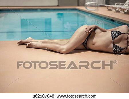Young woman in bikini relaxing beside swimming pool View Large Photo Image Stock Photo - Young woman in bikini relaxing beside swimming pool. Fotosearch