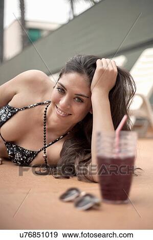 Stock Photo - Young woman in bikini relaxing beside deck chairs. Fotosearch