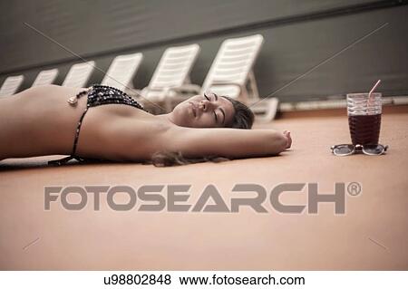 Young woman in bikini relaxing beside deck chairs View Large Photo Image Stock Photo - Young woman in bikini relaxing beside deck chairs. Fotosearch
