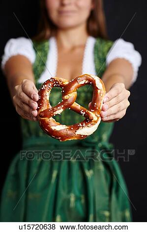Stock Photo - Young woman in Dirndl holding pretzel. Fotosearch