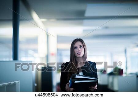 Young woman in office carrying ringbinder files looking away View Large Photo Image Picture - Young woman in office carrying ringbinder files looking away. Fotosearch