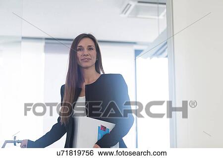 Young woman in office holding paperwork looking at camera smiling View Large Photo Image Stock Photograph - Young woman in office holding paperwork looking at camera smiling. Fotosearch