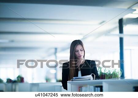 Young woman in office looking down at paperwork in ringbinder file View Large Photo Image Stock Photography - Young woman in office looking down at paperwork in ringbinder file. Fotosearch