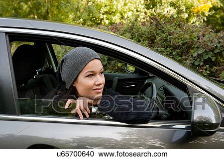 Young woman leaning and looking out from car window View Large Photo Image Stock Image - Young woman leaning and looking out from car window. Fotosearch