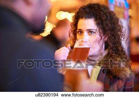 Picture - Young woman on night out drinking a glass of beer. Fotosearch