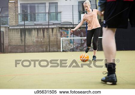 Young woman playing football on urban football pitch View Large Photo Image Stock Photography - Young woman playing football on urban football pitch. Fotosearch