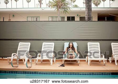 Young woman relaxing on deck chair beside swimming pool View Large Photo Image Stock Photo - Young woman relaxing on deck chair beside swimming pool. Fotosearch