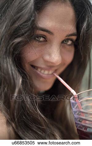 Stock Photography - Young woman sipping drink. Fotosearch