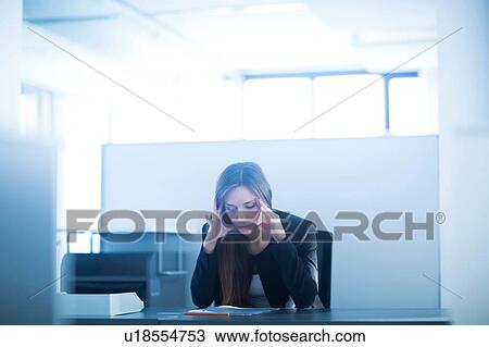 Young woman sitting at desk in office, head in hands looking down, stressed View Large Photo Image Stock Image - Young woman sitting at desk in office, head in hands looking down, stressed. Fotosearch