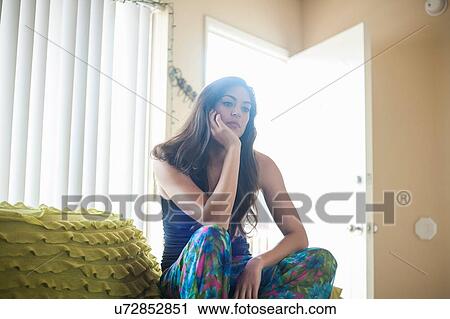 Young woman sitting resting on elbows, hand on chin, looking away View Large Photo Image Stock Image - Young woman sitting resting on elbows, hand on chin, looking away. Fotosearch