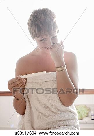 Picture - Young woman smiling at pregnancy test result. Fotosearch