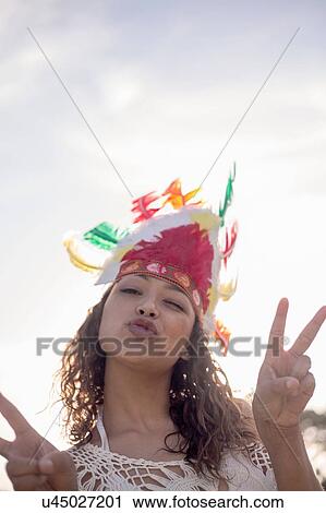 Stock Image - Young woman wearing feathered headdress. Fotosearch