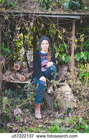 Young woman wearing knit hat sitting in firewood storage shed looking away View Large Photo Image Stock Photo - Young woman wearing knit hat sitting in firewood storage shed looking away. Fotosearch