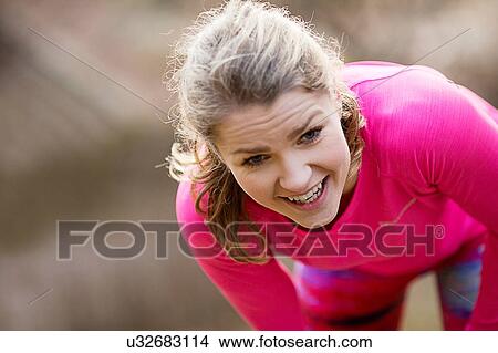 Picture - Young woman wearing sportswear bending over exhausted. Fotosearch
