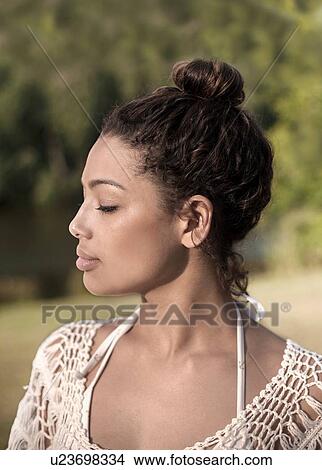 Young woman with hair bun, eyes closed View Large Photo Image Picture - Young woman with hair bun, eyes closed. Fotosearch
