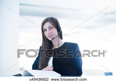 Young woman with paperwork wearing telephone headset looking away smiling View Large Photo Image Stock Image - Young woman with paperwork wearing telephone headset looking away smiling. Fotosearch