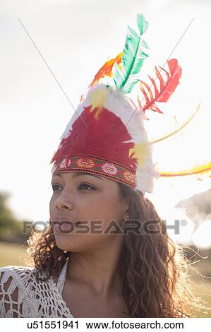 Stock Image - Young woman with wearing feathered headdress. Fotosearch
