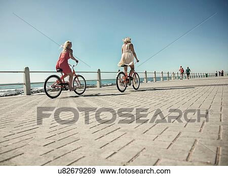 Stock Photo - Young women cycling on seafront, Cape Town, South Africa. Fotosearch