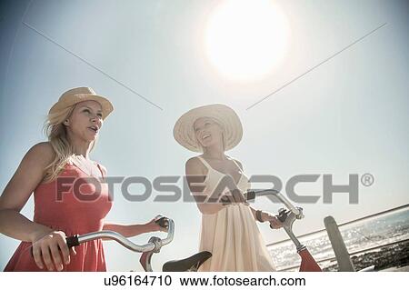 Young women walking with bicycle on seafront View Large Photo Image Stock Image - Young women walking with bicycle on seafront. Fotosearch