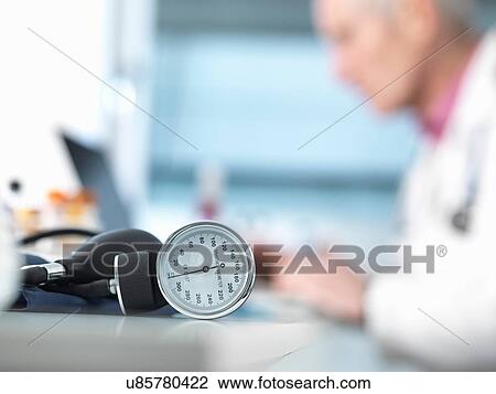 Blood pressure monitor on desk, doctor in background View Large Photo Image Stock Image - Blood pressure monitor on desk, doctor in background. Fotosearch