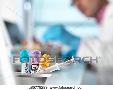 Stock Photo - Blood samples for medical testing on desk, doctor in background. Fotosearch