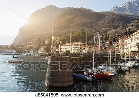 Stock Photography - Boats moored in sunlit harbor, Lake Como, Italy. Fotosearch