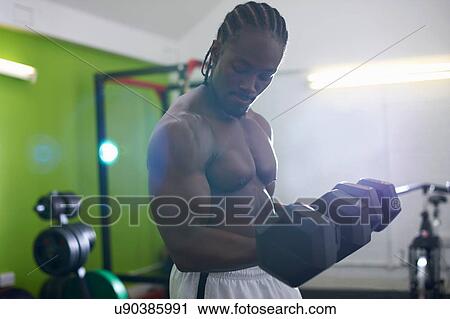 Stock Image - Bodybuilder lifting dumbbell in gym. Fotosearch