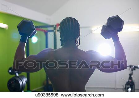 Stock Photo - Bodybuilder lifting dumbbell in gym. Fotosearch