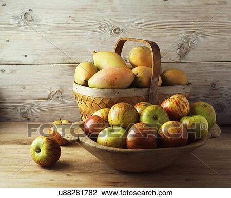 Stock Image - Bowl and basket of apples and mangos. Fotosearch