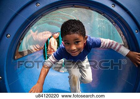 Boy bending forward emerging from playground tunnel View Large Photo Image Stock Image - Boy bending forward emerging from playground tunnel. Fotosearch