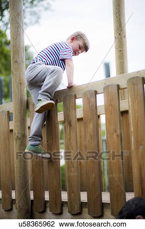 Boy climbing over wooden fence View Large Photo Image Stock Image - Boy climbing over wooden fence. Fotosearch